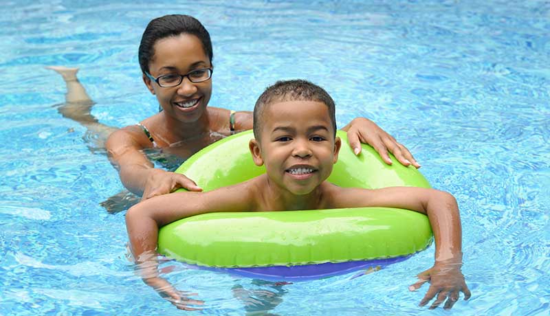 Mother and young boy in inner tube in swimming pool
