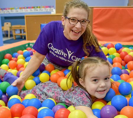 Cassandra and female therapist playing in ball pit