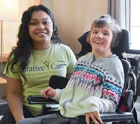 Mia sitting in wheelchair next to female service coordinator