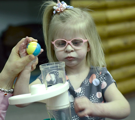 Olivia putting ball into toy