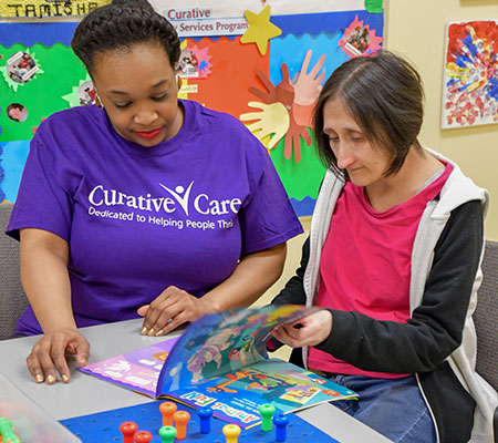 Sevie looking at magazine with female employee caregiver