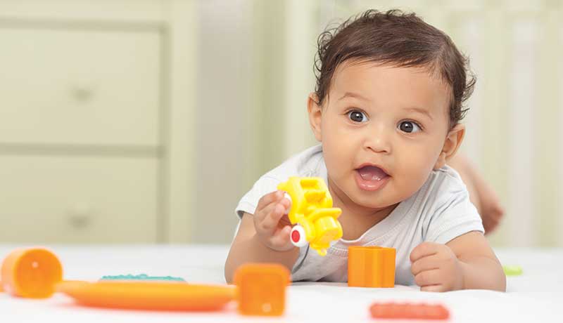 Young child laying on stomach playing with toys