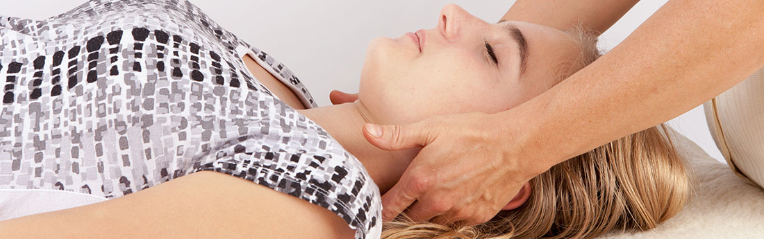 Female laying down, receiving massage therapy on neck